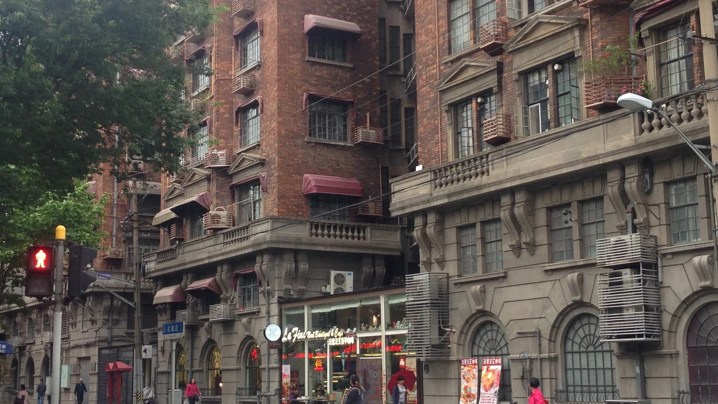 Trees shade Wukang Road beside historic buildings in Shanghai